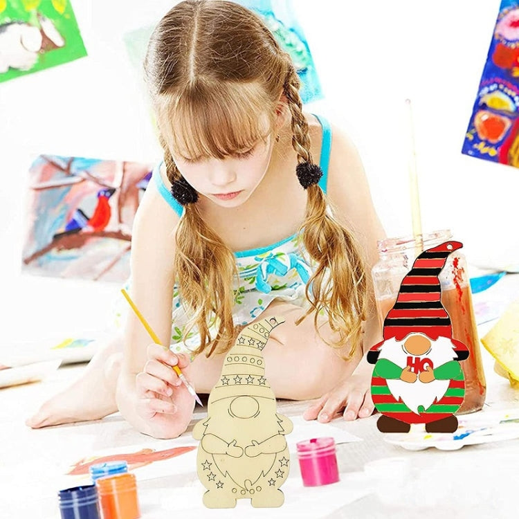 Child painting an unpainted wooden elf ornament on a table with hanging string