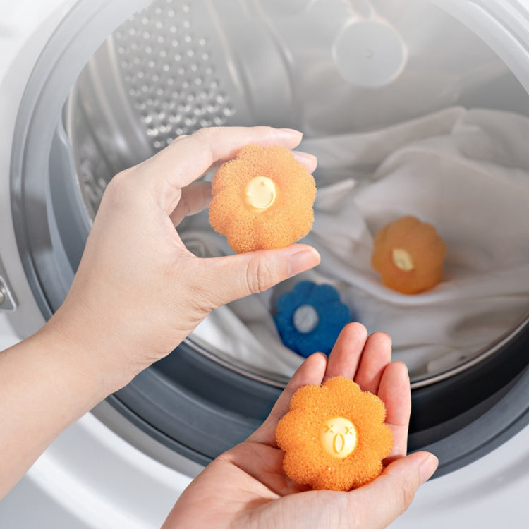 Orange and blue anti-tangle laundry cleaning balls in washer drum, shown in hands