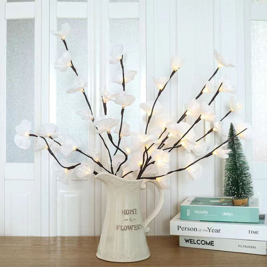 White butterfly orchid LED branch lights in a white vase on a tabletop