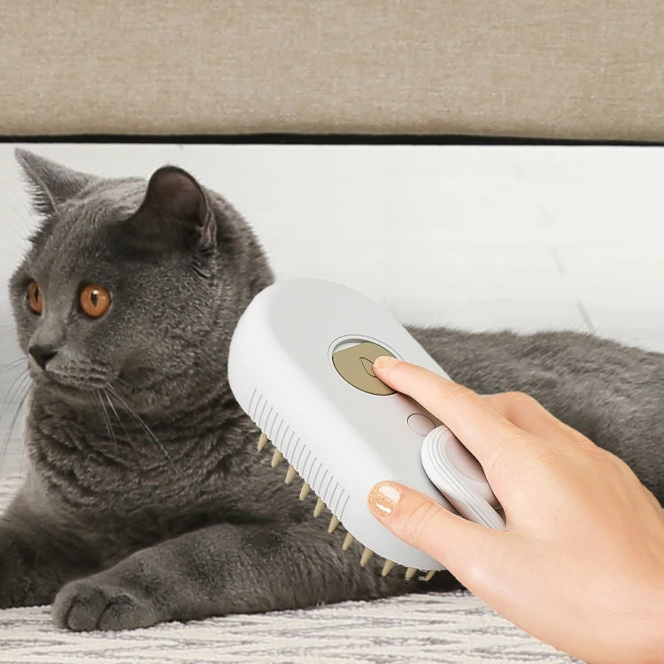 White electric grooming comb brushing a gray cat on a couch