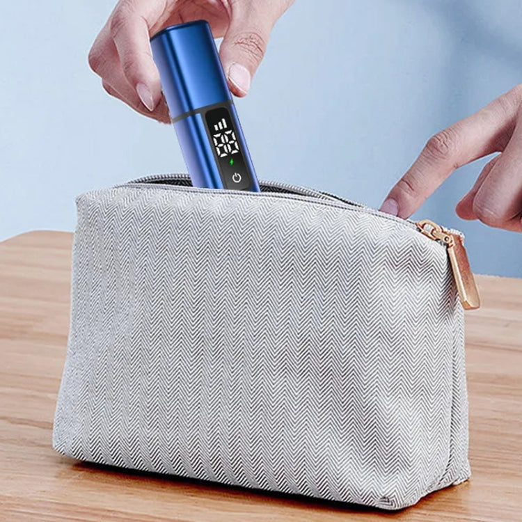 Handheld nose hair trimmer with digital screen, held above a travel toiletry bag