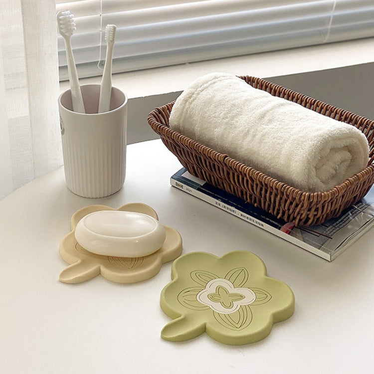 Green and beige flower-shaped silicone soap holders near towels and toothbrush cups.