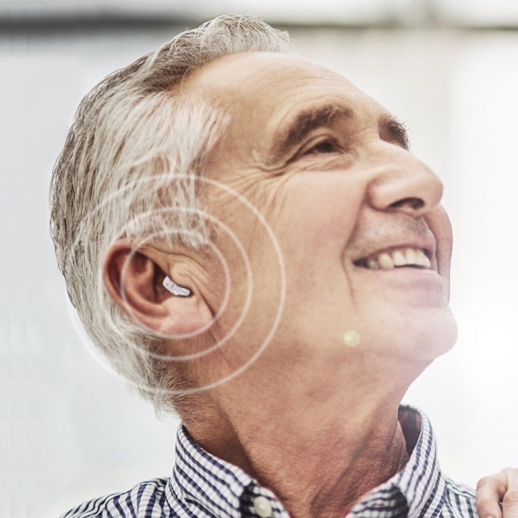 Elderly man wearing a small invisible in-ear hearing aid on one ear.