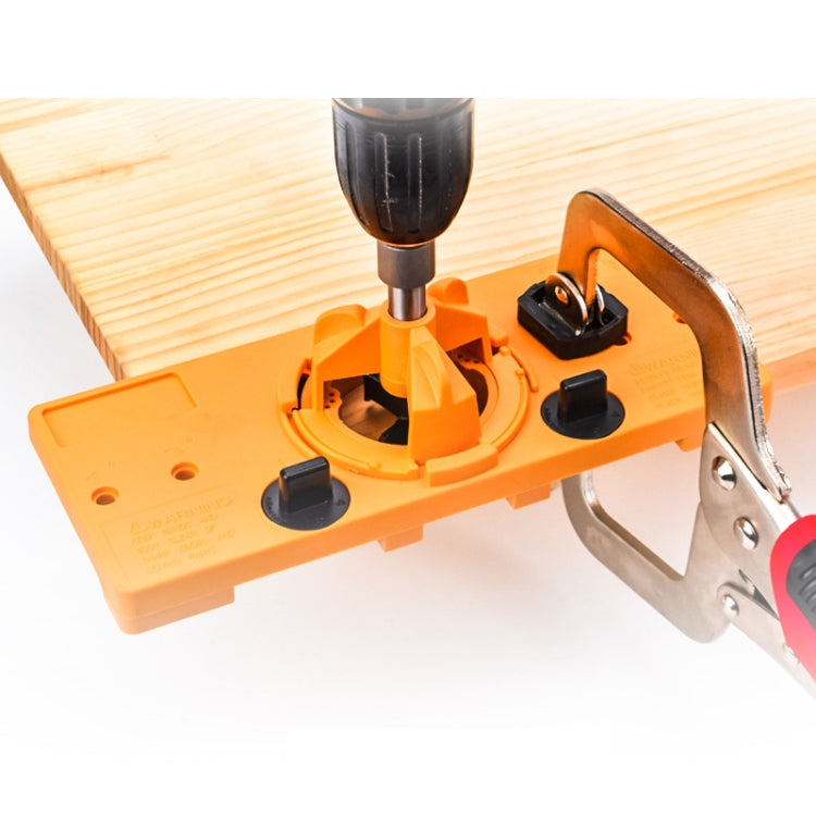 Orange 35mm hinge hole opener jig mounted on a wooden door panel