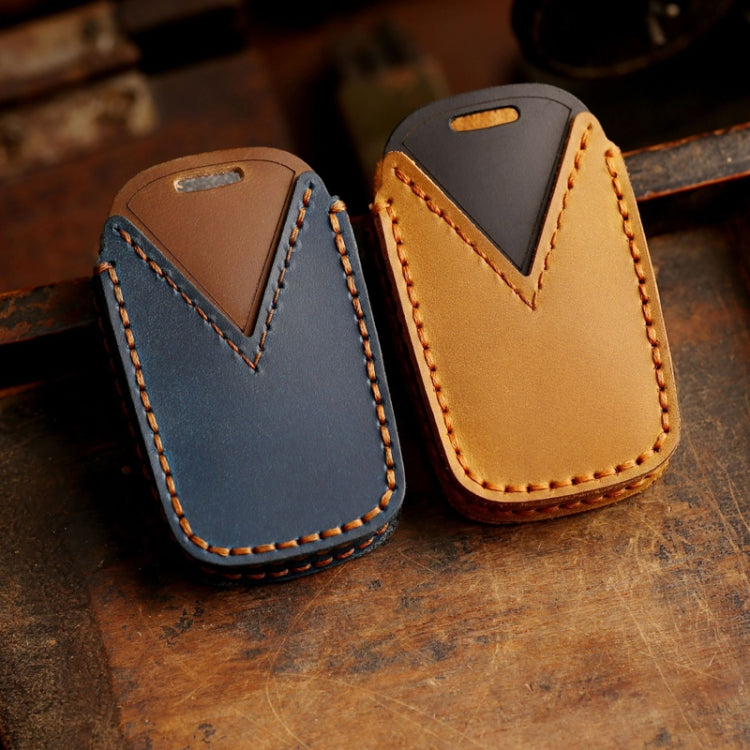 Blue and tan leather key fob covers with V-shaped panels, orange contrast stitching, and keyring loops