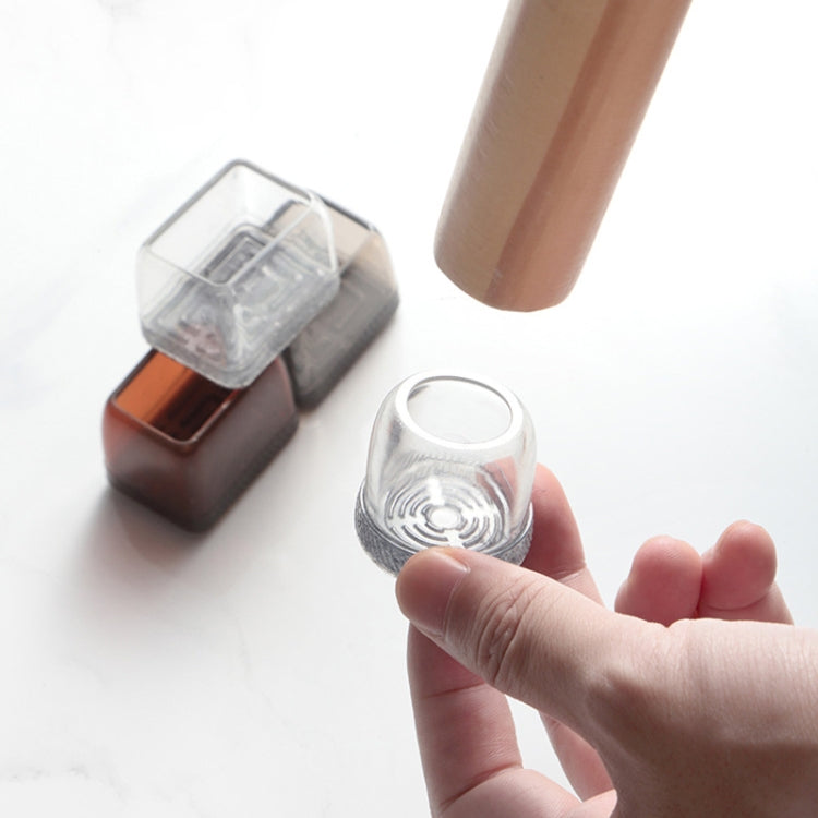 Small round and square furniture leg covers in transparent and brown, held in hand