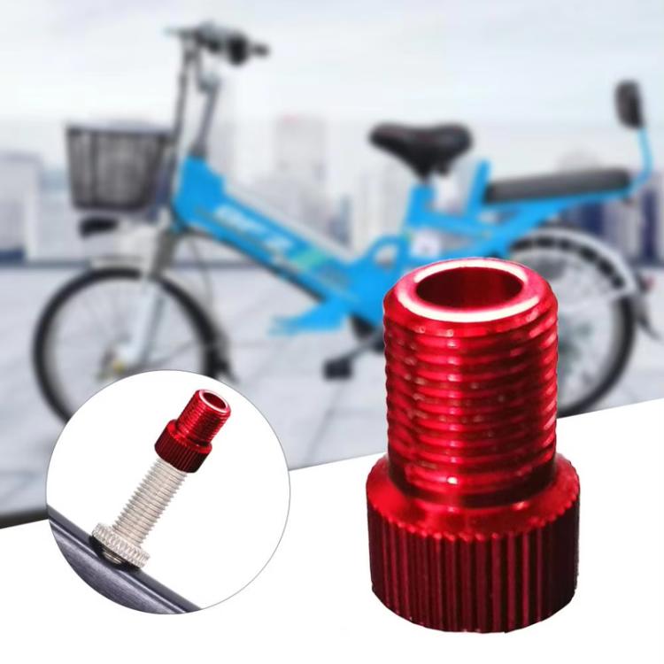 Red metal bicycle valve converter adapter with ribbed grip, close-up on valve