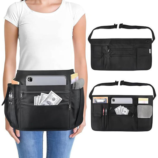 Black waist apron with front pockets and adjustable buckle strap, worn over denim.