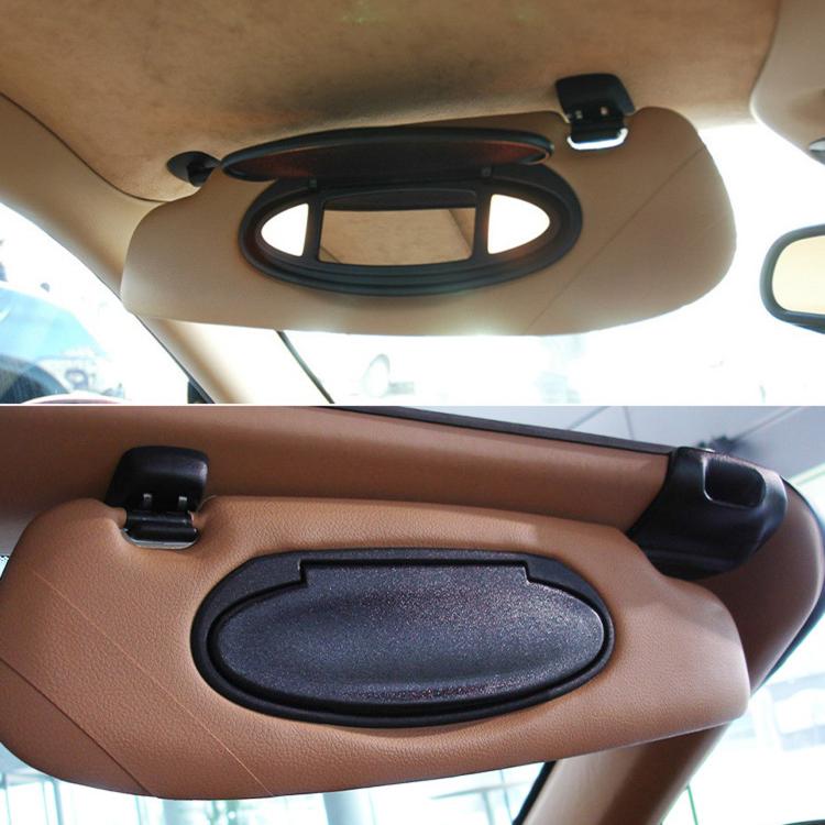 Black oval vanity mirror cover on car sun visor, installed on tan interior