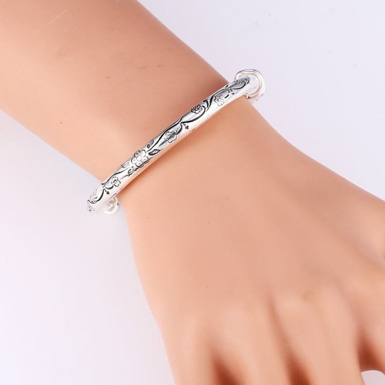 Silver floral carved cuff bracelet on wrist, slim open bangle