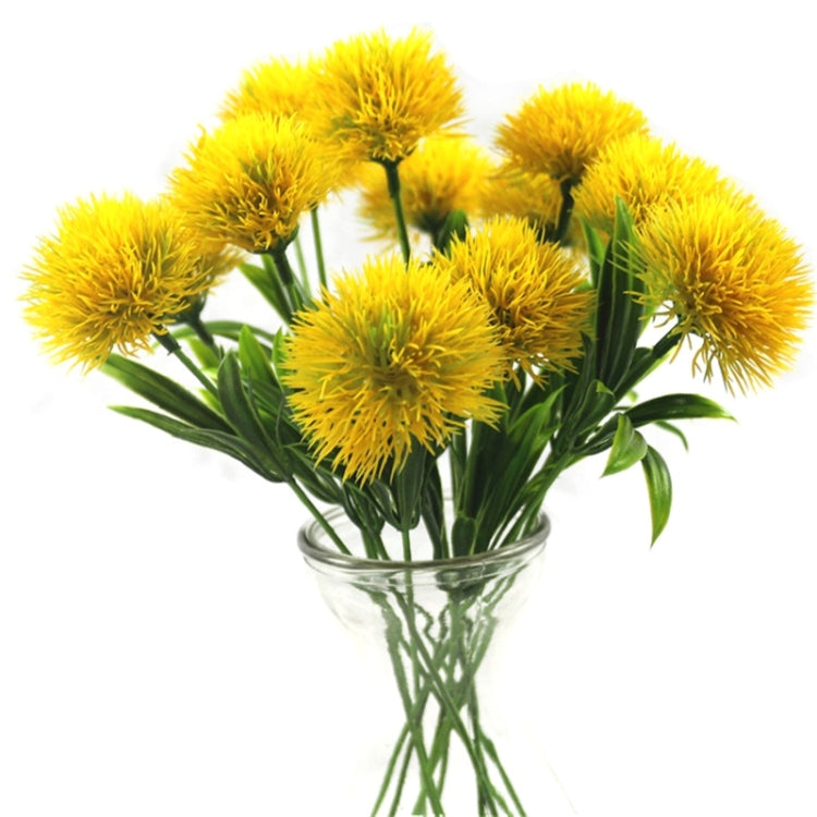 Yellow artificial dandelion flower bouquet with green plastic stems and glass vase