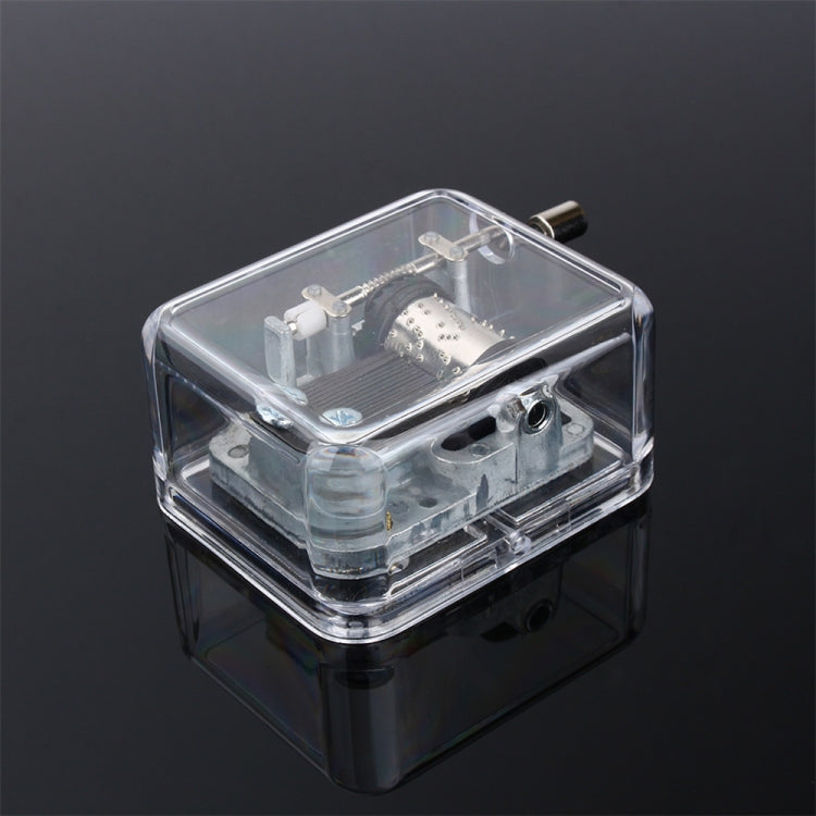 Clear acrylic DIY music box with exposed mechanism and crank handle, right-side view