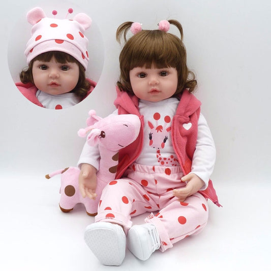Baby girl silicone doll wearing a pink hoodie and white patterned pajama set, holding a plush pink toy