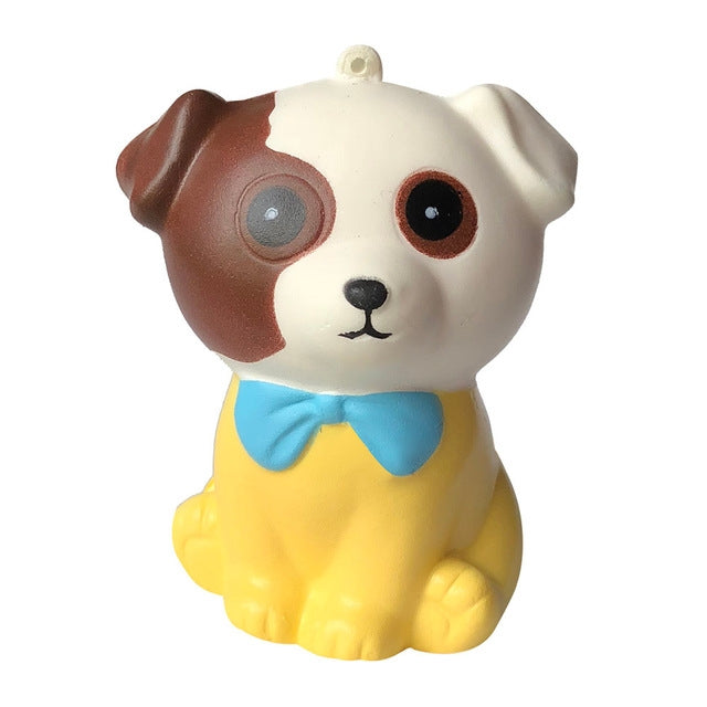 Squishy dog stress relief toy, cream body with brown patch, blue bow tie, round eyes.