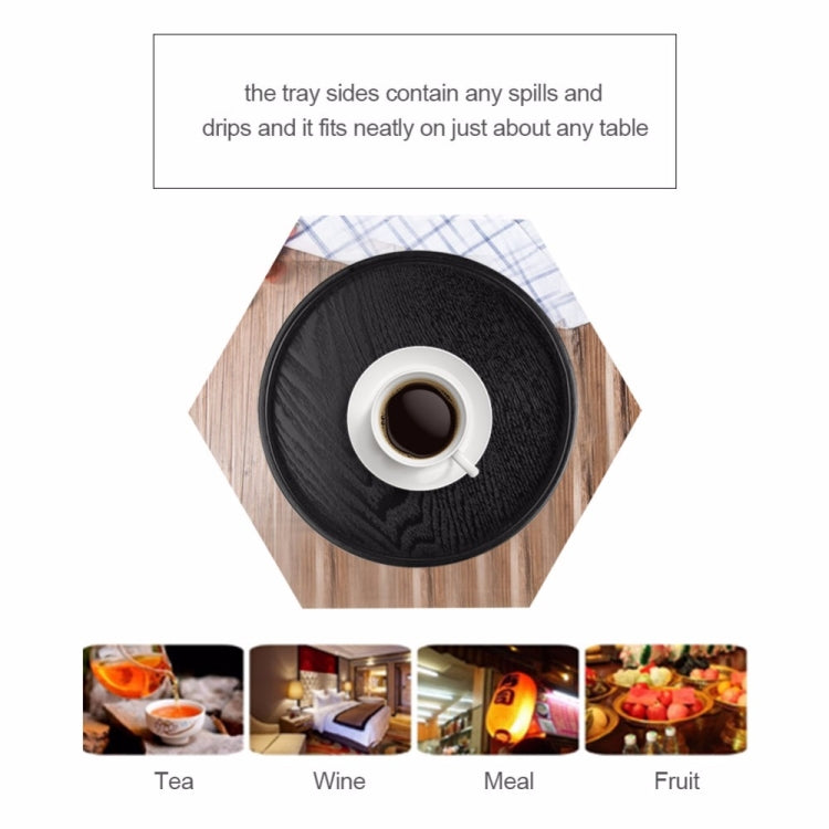 Round black wood tea tray holding a cup of tea on a table