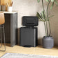 Black step-on kitchen trash can with hinged lid and ribbed body, pedal front