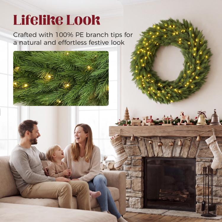 Pre-lit green Christmas wreath with warm LED lights above a stone fireplace.