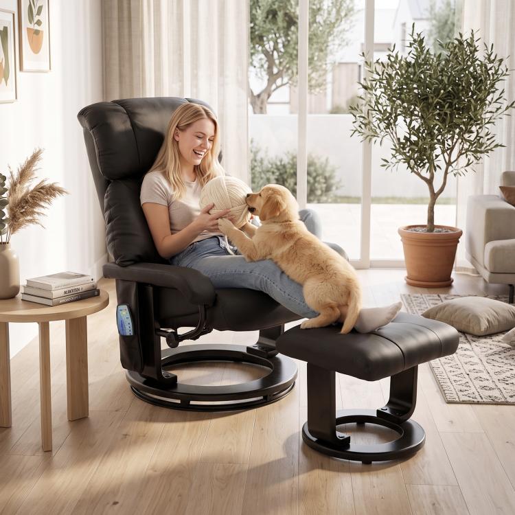 Black massage recliner with ottoman footstool holding a person and a small dog