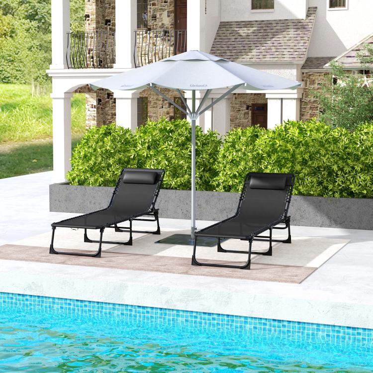Two black folding chaise lounge chairs with padded headrests for outdoor poolside lounging
