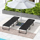 Two black folding chaise lounge chairs with mesh seat and adjustable backrests near an umbrella