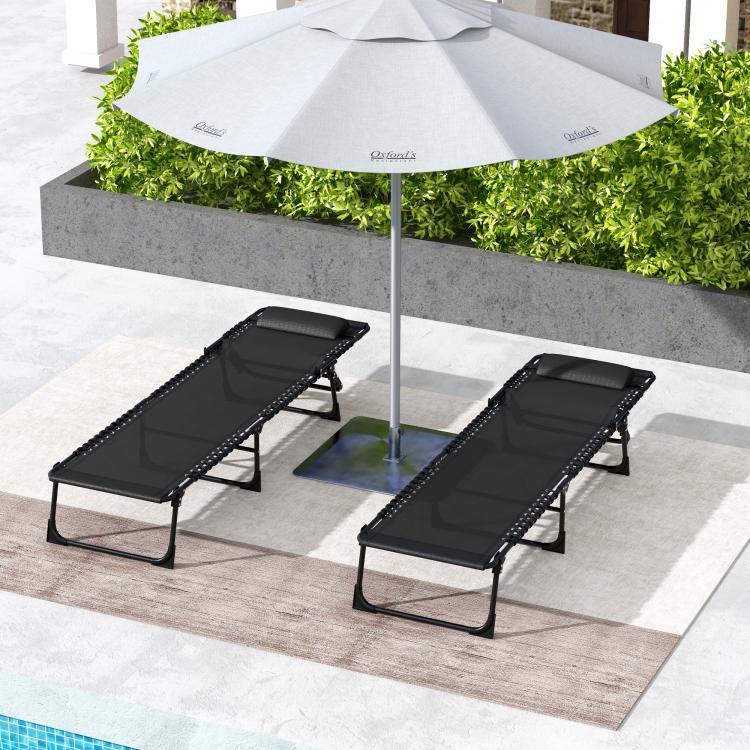 Two black folding chaise lounge chairs with mesh seat and adjustable backrests near an umbrella