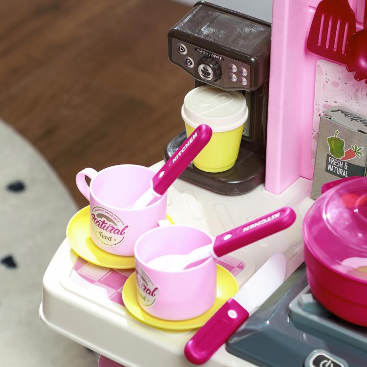 Kids play kitchen set with pink stovetop, pots, and cooking utensils on counter