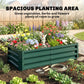 Green metal raised garden bed with slatted sides, planted with mixed flowers in a yard
