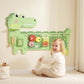 Green dinosaur activity board wall panel with gears, rods, and xylophone-style bars