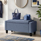 Dark blue-gray storage ottoman bench with tufted top, padded armrests, and wooden legs