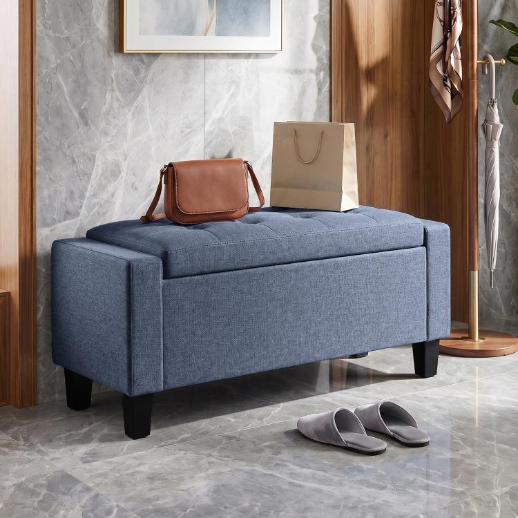 Dark blue-gray storage ottoman bench with tufted lid, armrests, and sturdy wooden legs