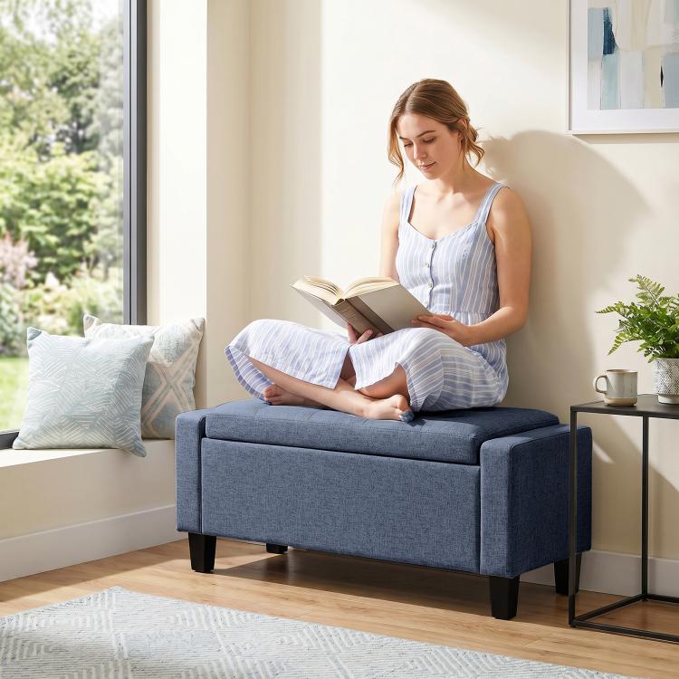 Dark blue-gray cushioned storage ottoman bench with wooden legs and side arm panels