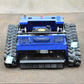 Blue remote-controlled crawler lawn mower with front grille and wide cutting deck