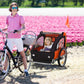 Orange and black 2-seat child bike trailer with two children seated inside