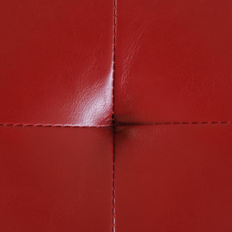 Red faux-leather ottoman corner with stitched seams and tufted panel