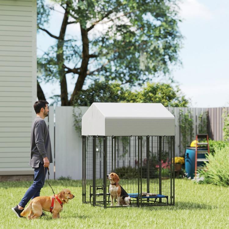 Outdoor dog kennel with white roof and black welded wire enclosure in backyard setting