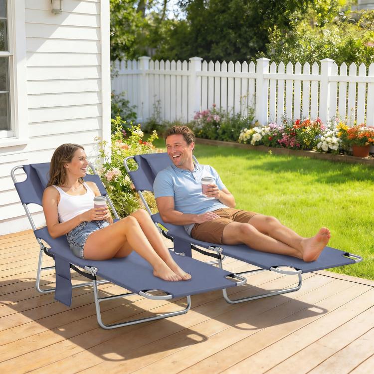 Two dark blue adjustable outdoor chaise lounges with face openings and padded headrests