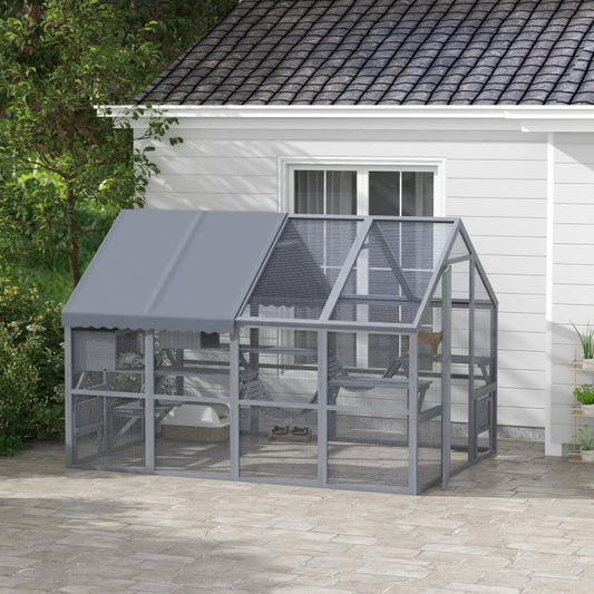 Gray outdoor cat enclosure with waterproof cover and mesh sides, shown beside a house wall