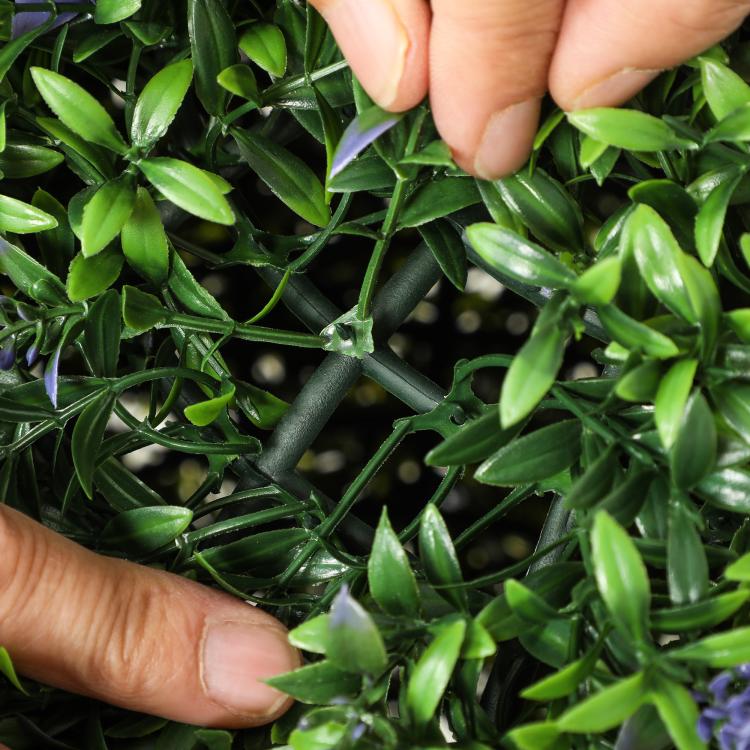 Artificial topiary ball with dense green leaves and purple accents, handheld close-up