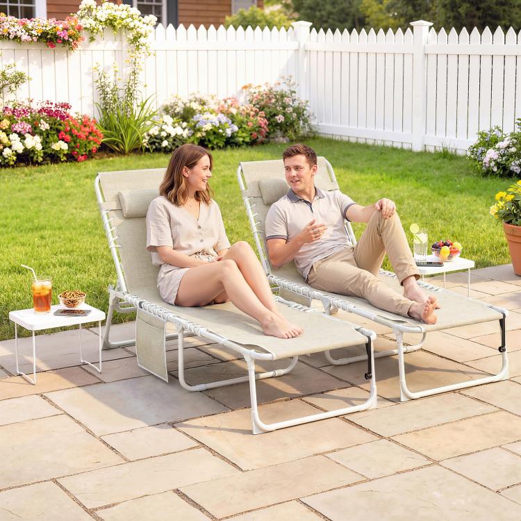 Pair of beige folding chaise lounge chairs with face holes, used outdoors