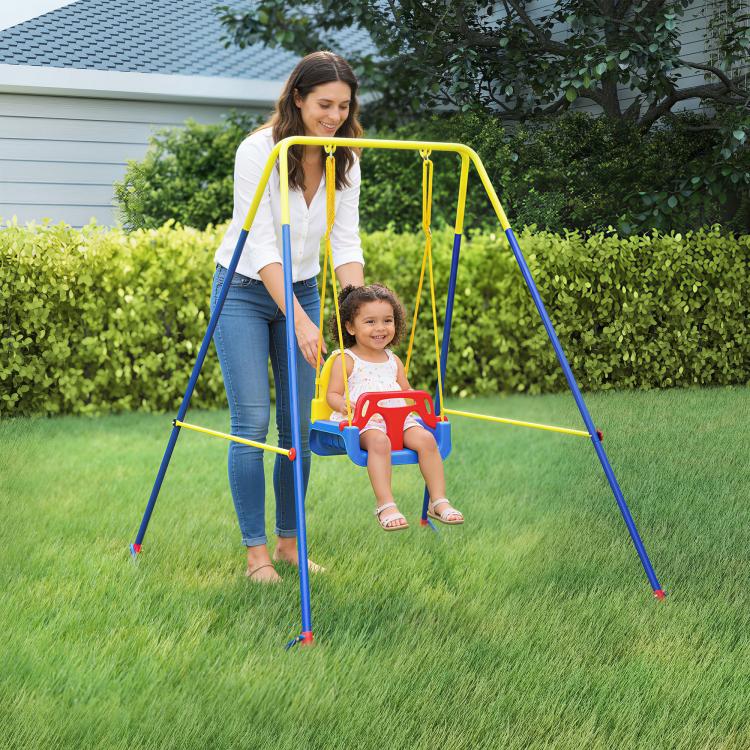 Toddler swing set with red seat and hanging ropes, with an adult holding the frame