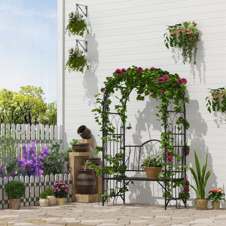 Black metal climbing arbor bench with arched trellis, green vines and red flowers