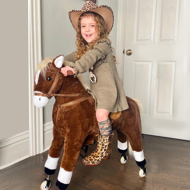 Brown plush ride-on walking horse with reins and rolling wheels, child riding