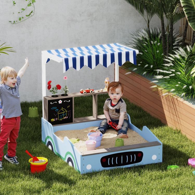 Blue kids sandbox with striped canopy and bench seats on backyard grass