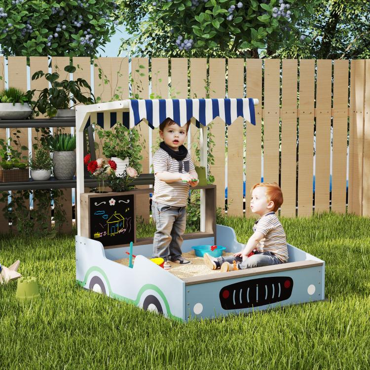 Blue kids wooden sandbox with striped canopy and bench seats in garden yard