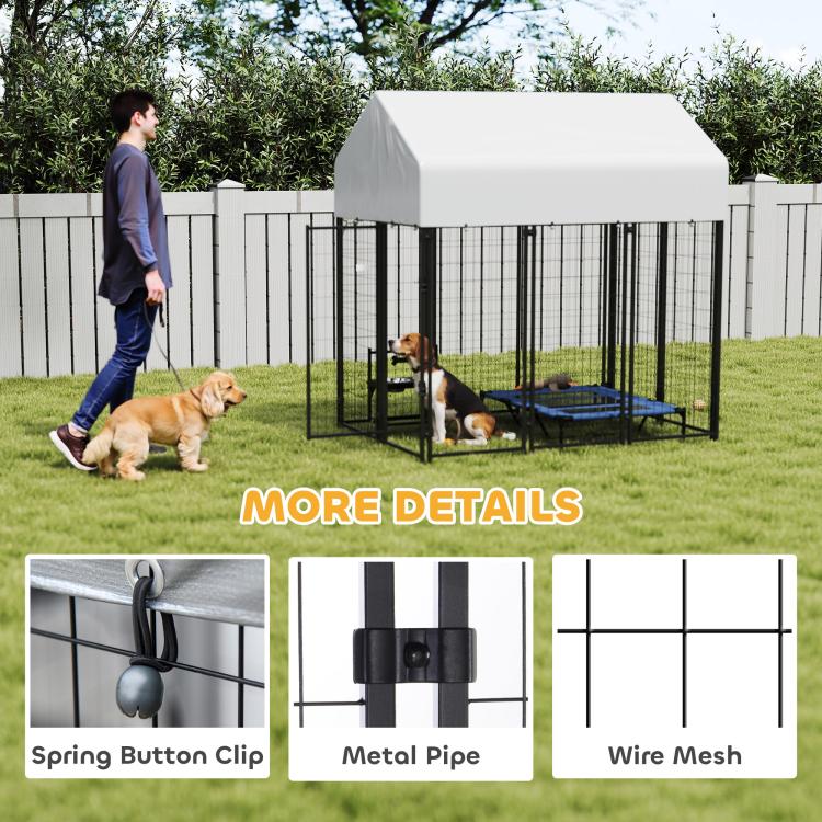 Outdoor dog kennel with peaked roof and black wire panels, two dogs and blue mat inside.