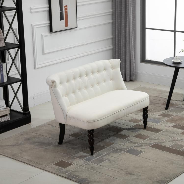 Cream button-tufted armless loveseat with dark wood legs, in a living room setting