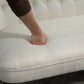 Close-up of cream loveseat seat cushion with foot resting on upholstery