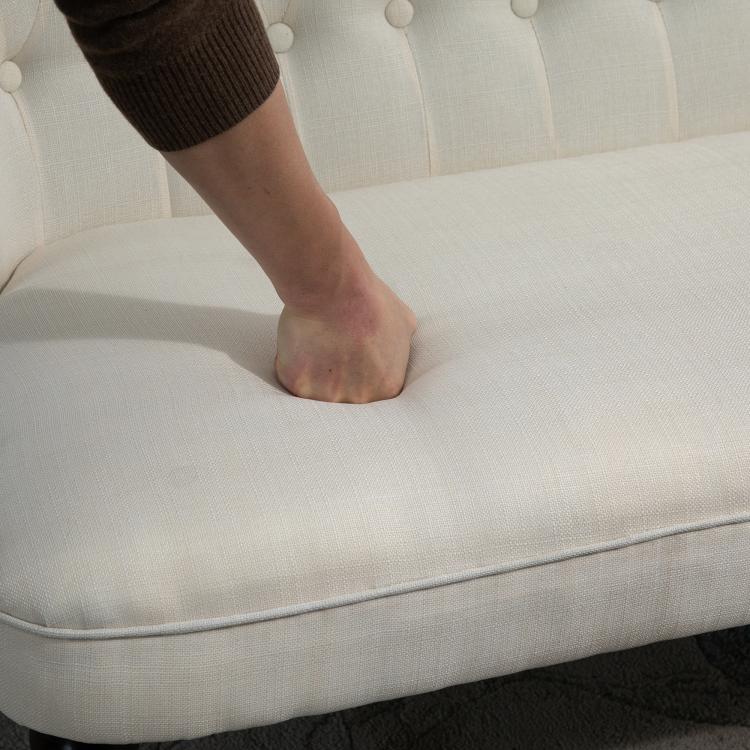 Close-up of cream loveseat seat cushion with foot resting on upholstery