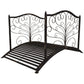 Dark bronze metal arched garden bridge with scrollwork panels and ribbed slat walking deck.