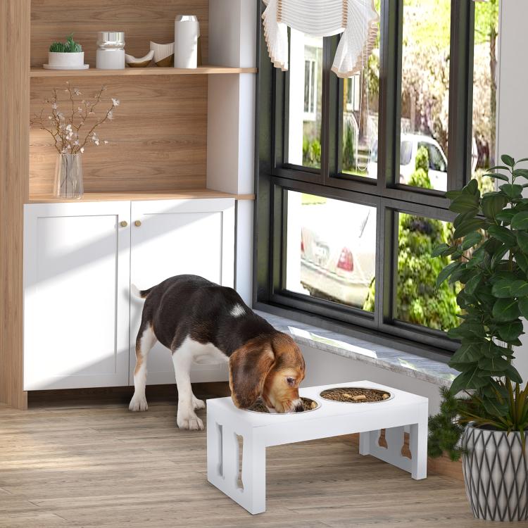 White elevated dog feeding station with two stainless steel bowls in a home setting
